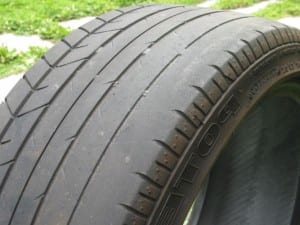 Car tire showing uneven inner shoulder wear caused by improper wheel alignment or incorrect camber settings.